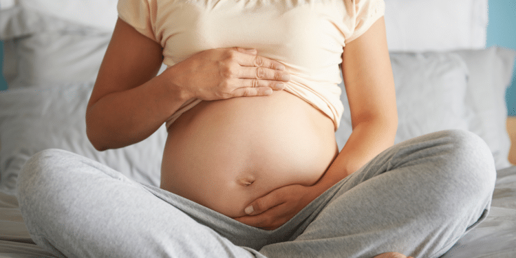 Mulher grávida sentada e segurando a sua barriga como se estivesse acariciando