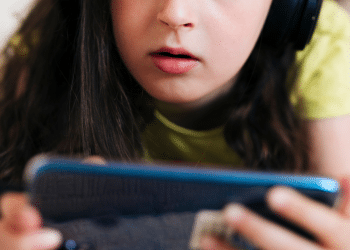 Criança de fone jogando no celular