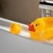 3 patos de borracha na beira de uma banheira representando o banho das crianças.