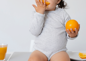 Criança chupando uma laranja