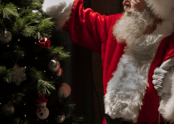 Papael Noel ao lado de uma árvore de natal