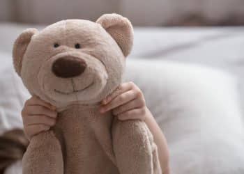 Criança com urso de pelúcia representando a parentalidade intensiva.