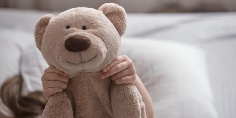 Criança com urso de pelúcia representando a parentalidade intensiva.