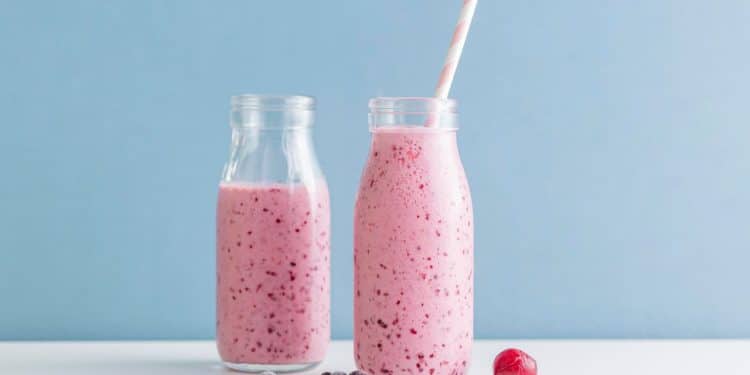 Smoothies de frutas vermelhas em frente a um fundo azul.