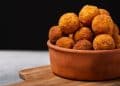 Bolinho de arroz em tigela marrom em frente a um fundo preto.