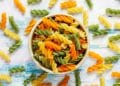 Macarrão salada em uma tigela com macarrões em volta.