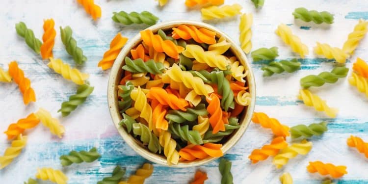 Macarrão salada em uma tigela com macarrões em volta.