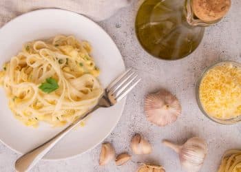 Prato de macarrão ao alho e óleo com ingredientes em volta.