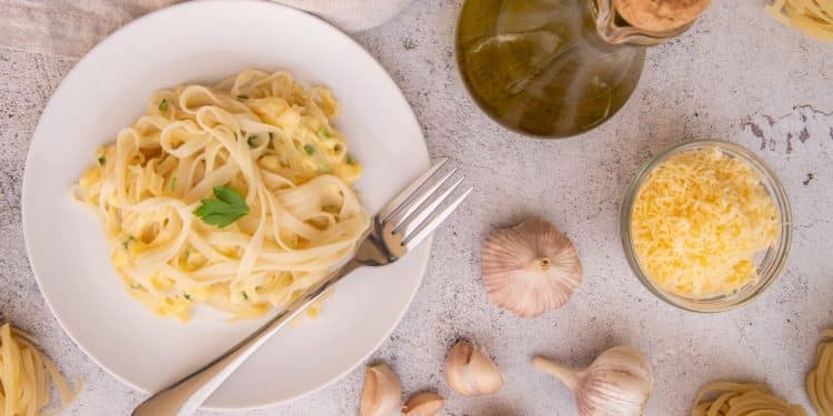 Prato de macarrão ao alho e óleo com ingredientes em volta.