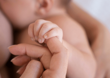 mãe amentando o bebê e ele está segurando o dedo dela