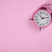 Relógio que remete um alarme em uma parede de fundo rosa