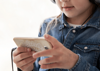 Criança mexendo no celular com um fone de ouvido