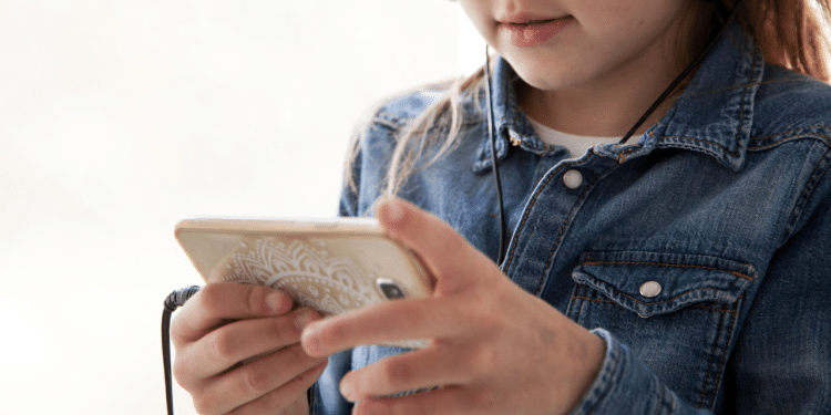 Criança mexendo no celular com um fone de ouvido
