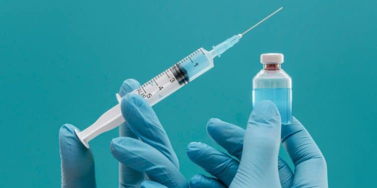 Mãos segurando vacinas em um fundo azul.