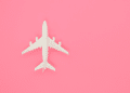 Imagem de uma miniatura de avião em um fundo rosa
