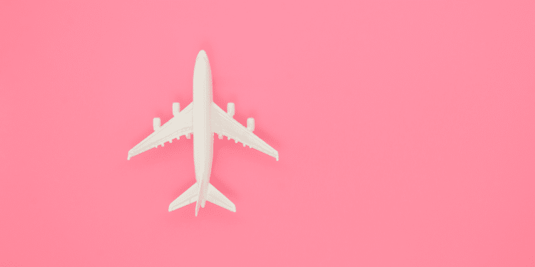 Imagem de uma miniatura de avião em um fundo rosa