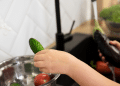 Uma mão lavando verduras