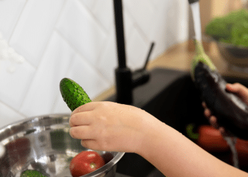 Uma mão lavando verduras