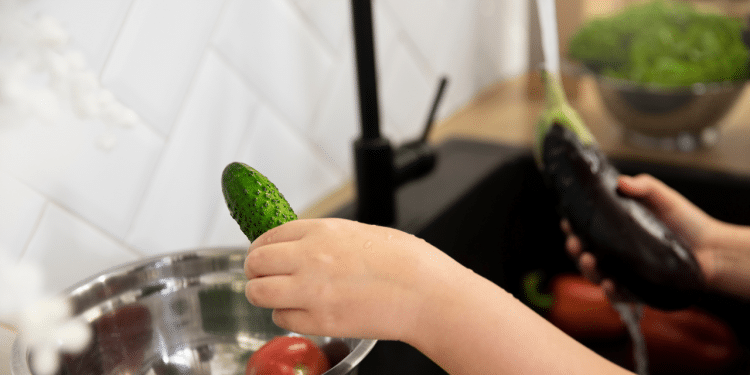 Uma mão lavando verduras
