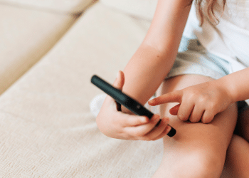 Mão de criança mexendo no celular