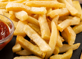 batata frita em um prato preto com ketchup do lado