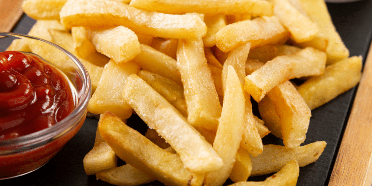 batata frita em um prato preto com ketchup do lado