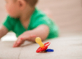 Criança próximo a chupeta que está no chão