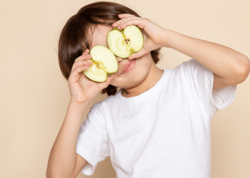 menino com maçã cortada tampando os olhos