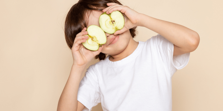 menino com maçã cortada tampando os olhos