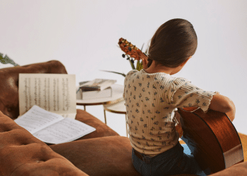 Menina aprendendo a tocar violão em casa