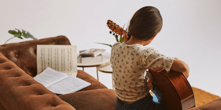 Menina aprendendo a tocar violão em casa