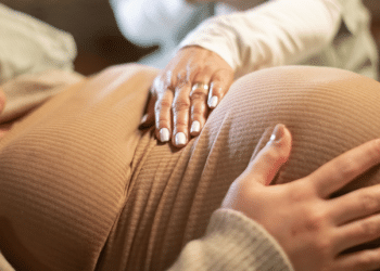 Mulher grávida deitada com as mãos na barriga