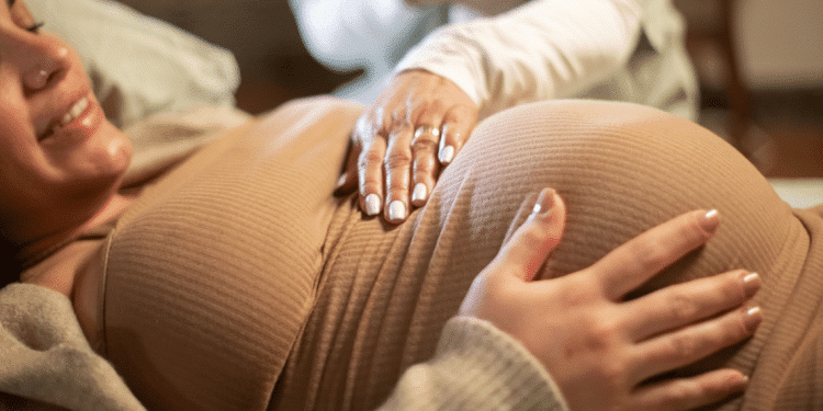 Mulher grávida deitada com as mãos na barriga