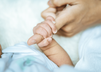 Recém nascido segurando o dedo de um adulto