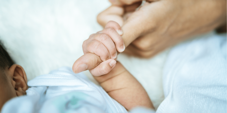 Recém nascido segurando o dedo de um adulto