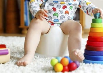 Criança sentada no penicoe enquanto brinca