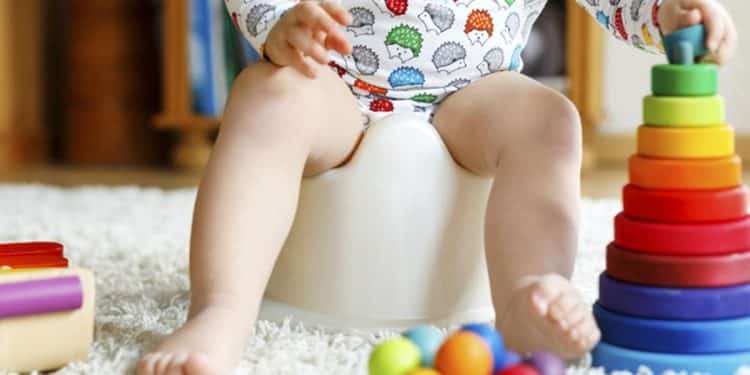 Criança sentada no penicoe enquanto brinca