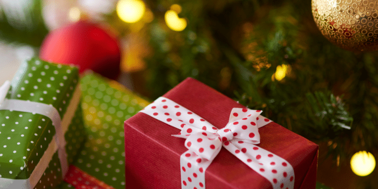 Arvóre de natal com presentes embaixo, uma caixa vermelha e uma verde, na árvore há enfeites, como bolas e luzes