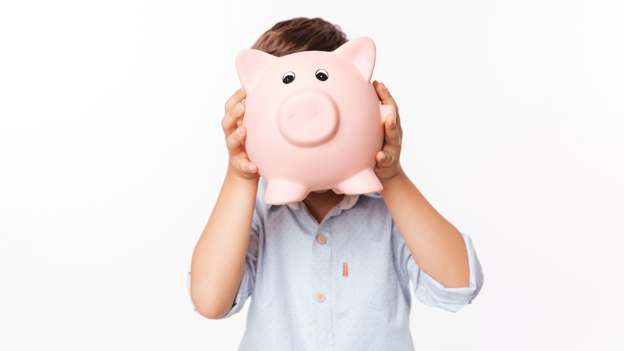 Criança segurando um cofrinho em forma de porco